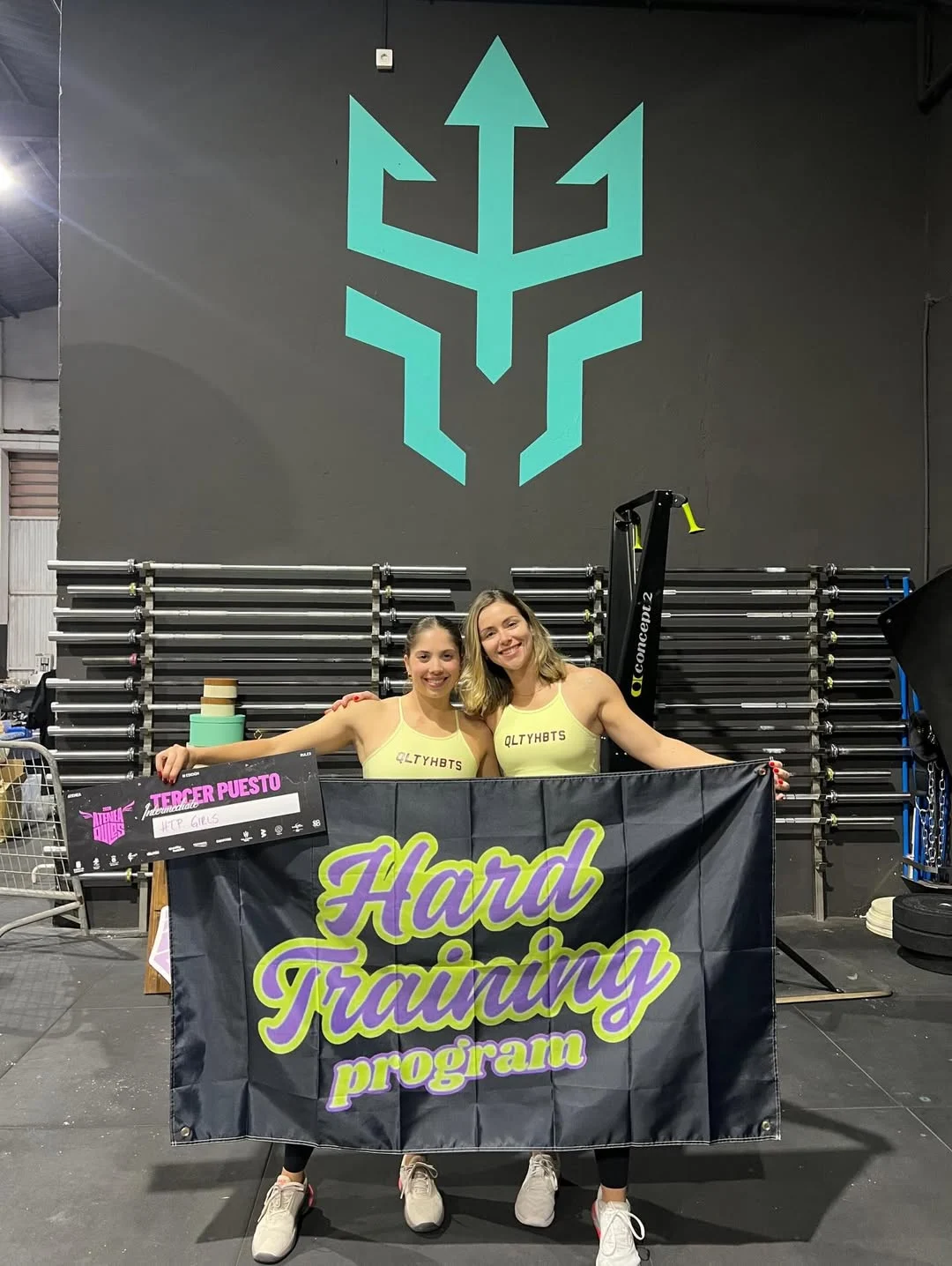 Atletas de Hard Training Program celebrando con la bandera del equipo bajo el tridente cian